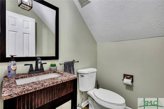 bathroom with vanity, toilet, and lofted ceiling