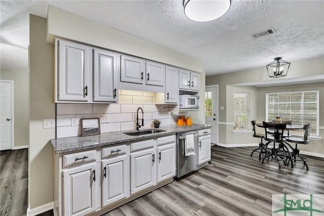 kitchen with dishwasher, decorative backsplash, a textured ceiling, and sink