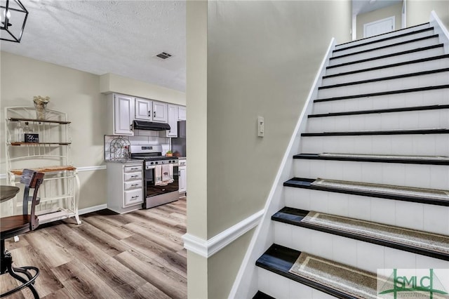 staircase with hardwood / wood-style floors and a textured ceiling