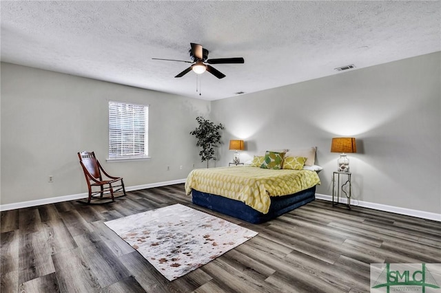 bedroom with ceiling fan, dark hardwood / wood-style floors, and a textured ceiling