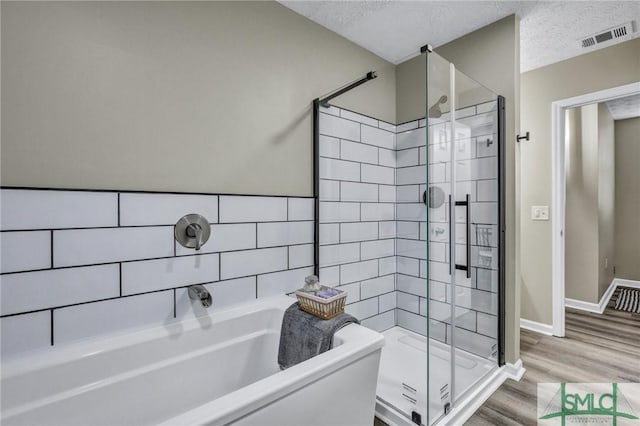 bathroom with independent shower and bath, a textured ceiling, and hardwood / wood-style flooring