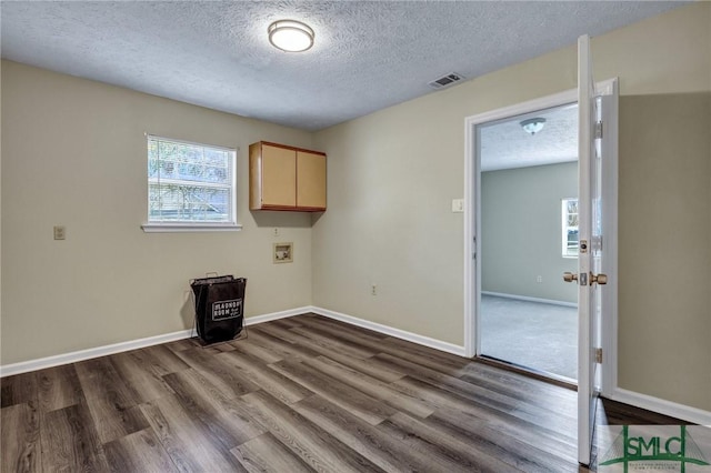 clothes washing area featuring cabinets, dark hardwood / wood-style flooring, washer hookup, and a textured ceiling