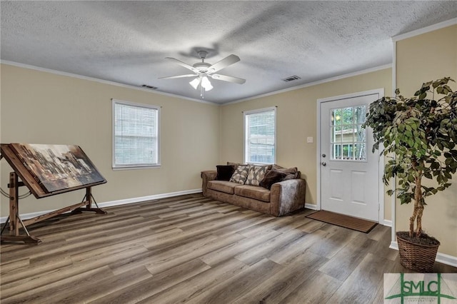 living room featuring a textured ceiling, hardwood / wood-style flooring, ceiling fan, and ornamental molding