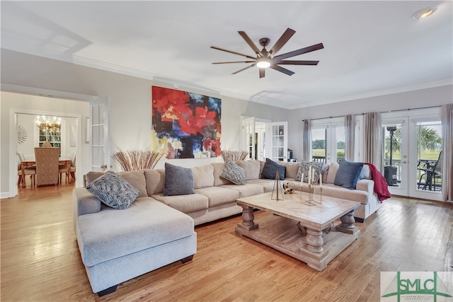 living room with ceiling fan with notable chandelier, french doors, light wood-type flooring, and ornamental molding