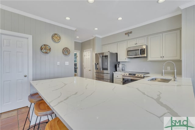 kitchen featuring light stone countertops, ornamental molding, stainless steel appliances, sink, and white cabinetry