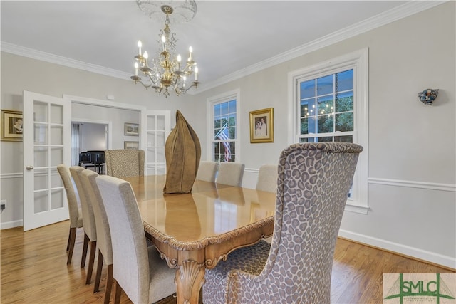 dining room featuring french doors, an inviting chandelier, light hardwood / wood-style flooring, and ornamental molding