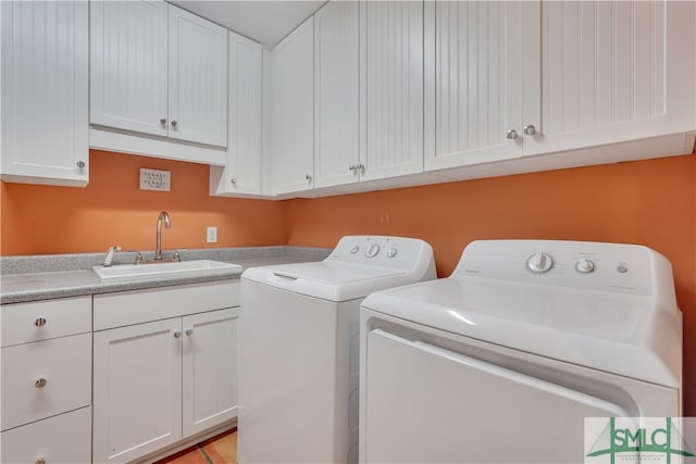 clothes washing area featuring washing machine and clothes dryer, sink, and cabinets