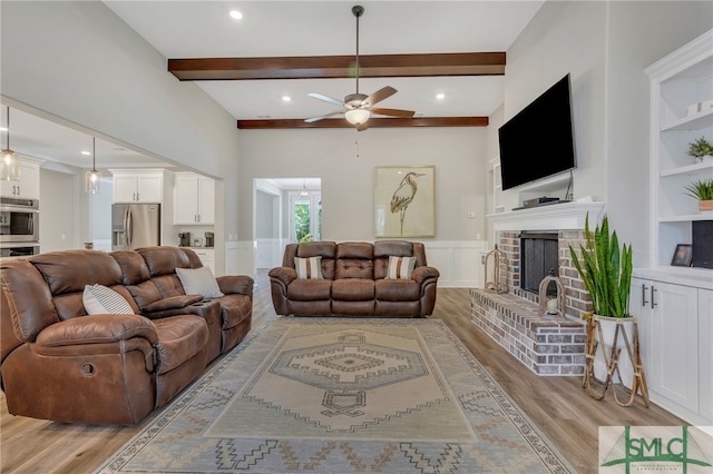 living room featuring light wood-type flooring, a brick fireplace, ceiling fan, built in features, and beamed ceiling