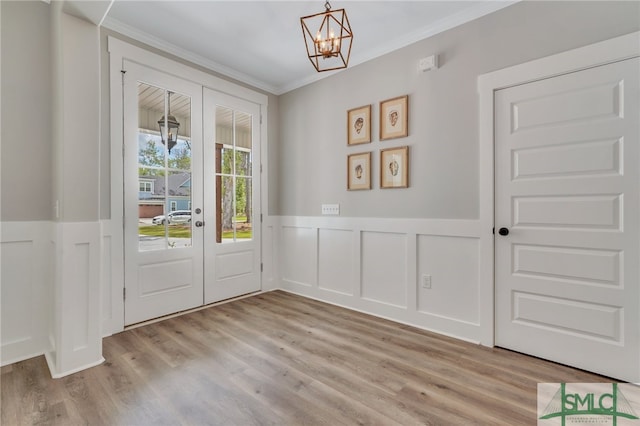 doorway to outside with a notable chandelier, light hardwood / wood-style floors, and crown molding