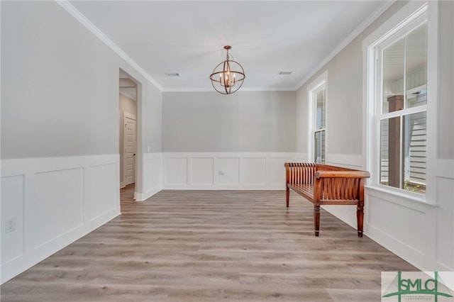 interior space featuring ornamental molding, a notable chandelier, and light wood-type flooring