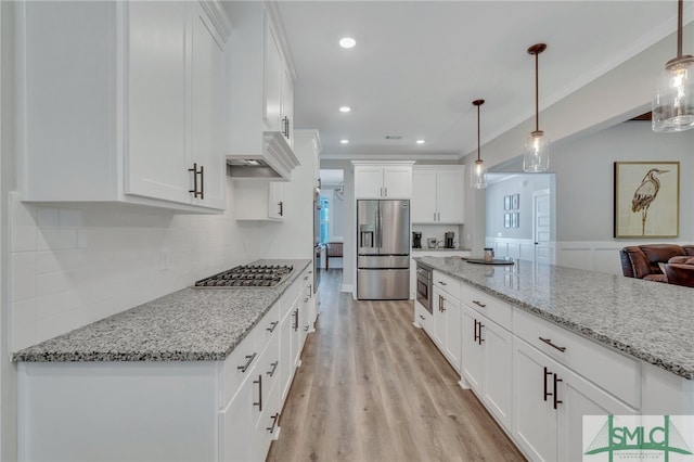 kitchen featuring white cabinets, light hardwood / wood-style floors, hanging light fixtures, and appliances with stainless steel finishes