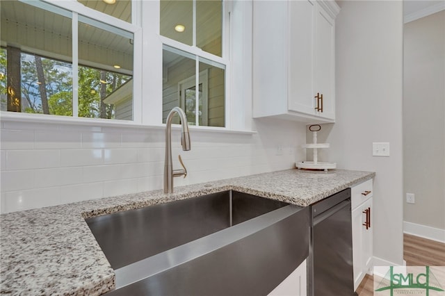 kitchen featuring light stone countertops, sink, white cabinets, and stainless steel dishwasher