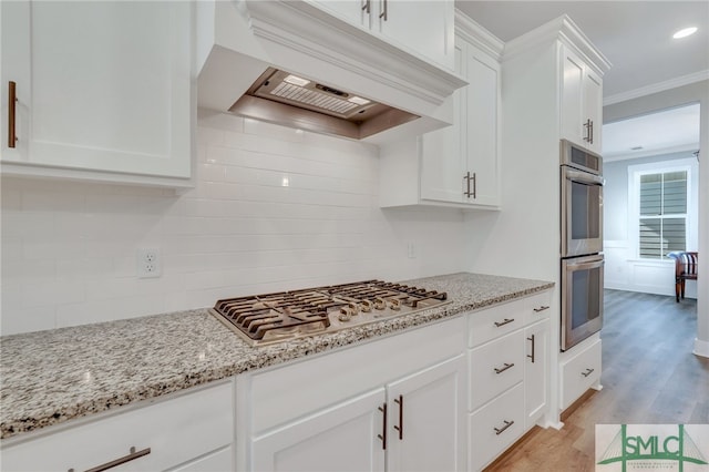 kitchen featuring white cabinetry, tasteful backsplash, light stone counters, light hardwood / wood-style flooring, and appliances with stainless steel finishes