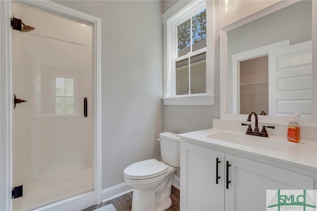 bathroom featuring wood-type flooring, vanity, toilet, and a shower with door