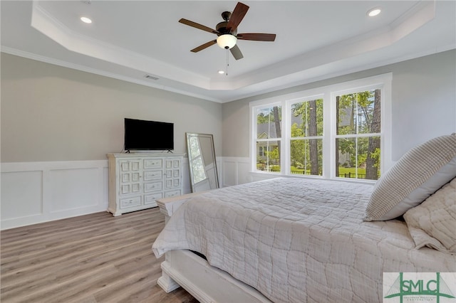 bedroom featuring a tray ceiling, crown molding, ceiling fan, and light hardwood / wood-style floors