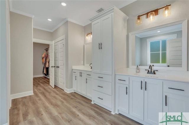 bathroom featuring wood-type flooring, vanity, and ornamental molding