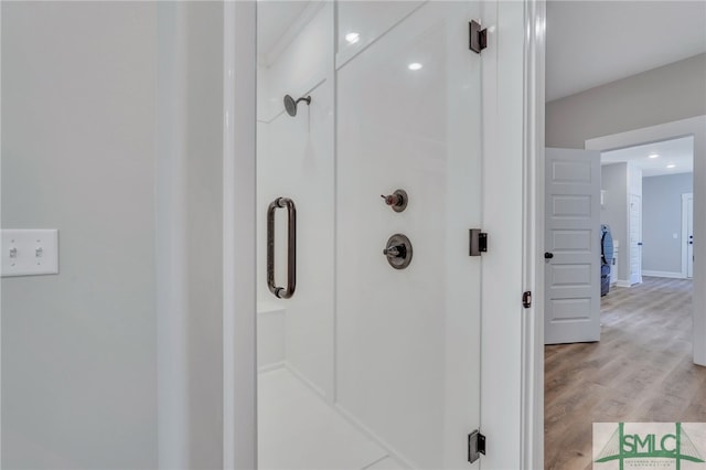 bathroom with hardwood / wood-style flooring and a shower with shower door