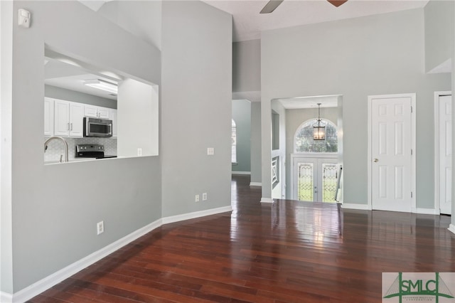 interior space featuring ceiling fan, dark hardwood / wood-style flooring, a high ceiling, and french doors