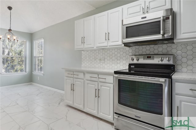 kitchen with white cabinets, decorative backsplash, lofted ceiling, and stainless steel appliances