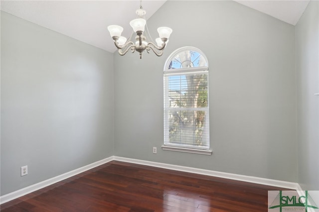 spare room featuring vaulted ceiling, dark wood-type flooring, and an inviting chandelier