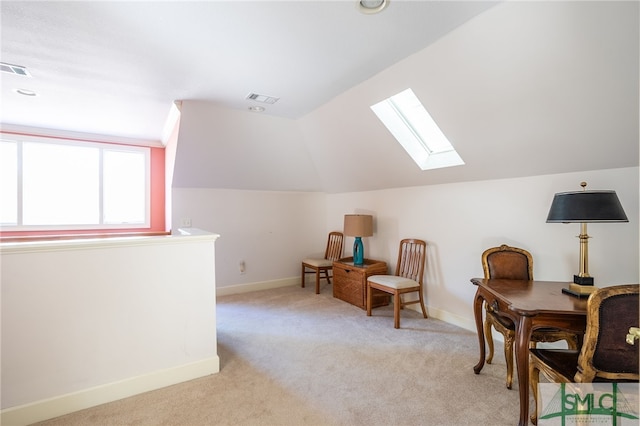 sitting room with light colored carpet and vaulted ceiling with skylight