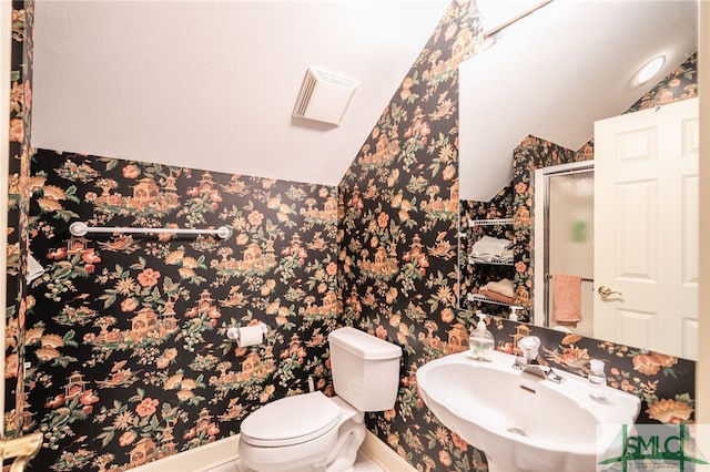 bathroom with lofted ceiling, toilet, a shower with shower door, and sink