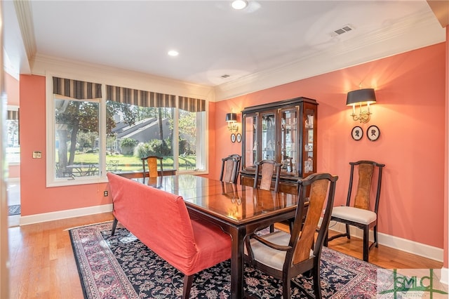 dining space featuring crown molding and light hardwood / wood-style flooring