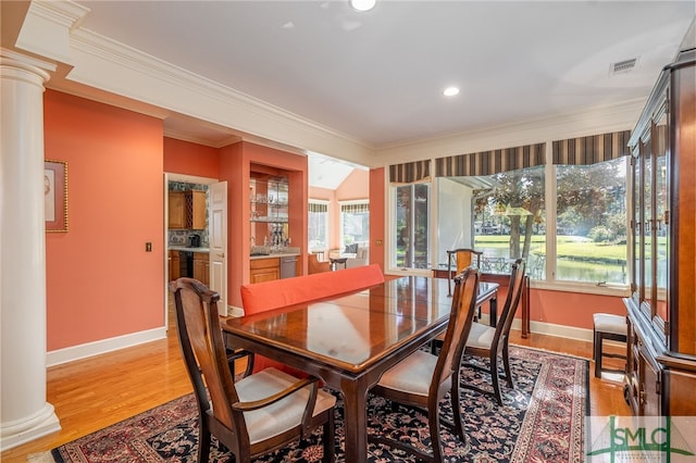 dining room featuring ornate columns, ornamental molding, and light wood-type flooring