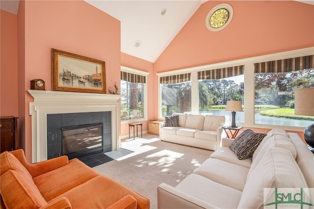 carpeted living room featuring a tiled fireplace and high vaulted ceiling