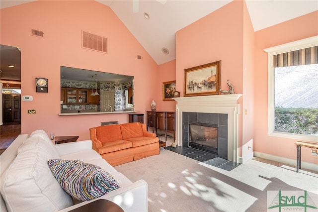 living room with dark carpet, high vaulted ceiling, and a tile fireplace