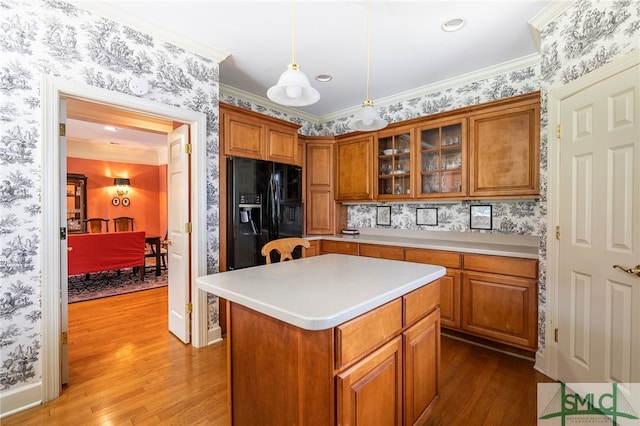 kitchen featuring ornamental molding, a kitchen island, black refrigerator with ice dispenser, and hanging light fixtures