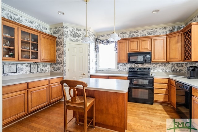 kitchen with hanging light fixtures, a center island, light hardwood / wood-style floors, and black appliances