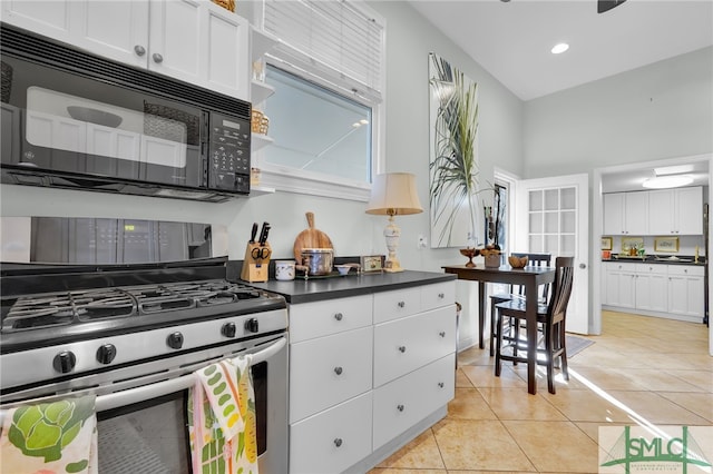 kitchen with light tile patterned flooring, white cabinetry, a towering ceiling, and stainless steel gas range