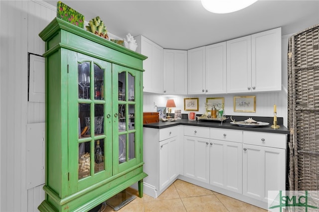 kitchen featuring light tile patterned floors, white cabinetry, and wooden walls