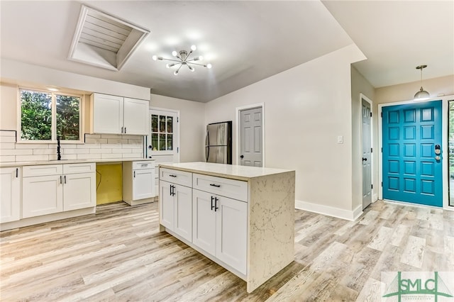 kitchen featuring white cabinets, pendant lighting, decorative backsplash, and light hardwood / wood-style flooring