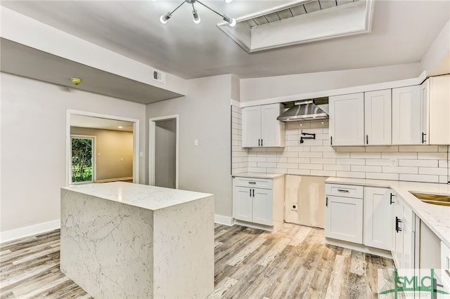 kitchen featuring light stone countertops, white cabinetry, tasteful backsplash, and light hardwood / wood-style flooring