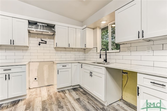 kitchen with tasteful backsplash, sink, white cabinets, and light hardwood / wood-style floors