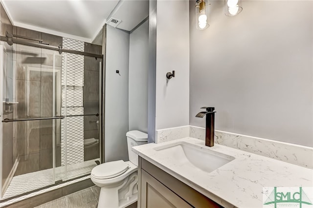 bathroom featuring an enclosed shower, vanity, and toilet