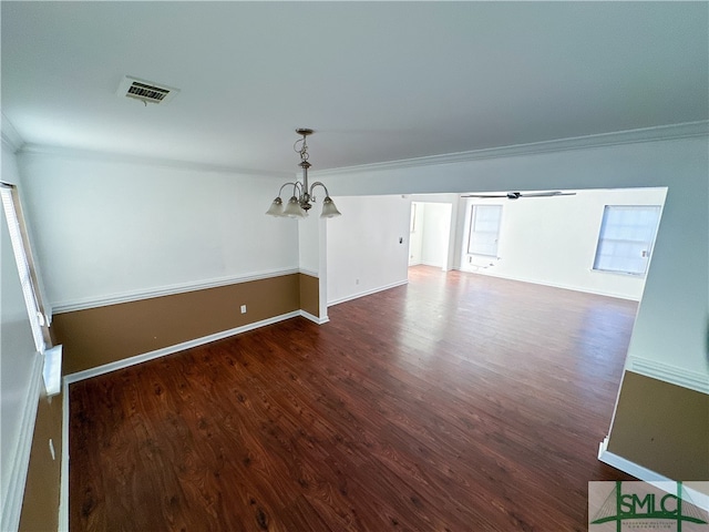 unfurnished room featuring dark hardwood / wood-style floors, an inviting chandelier, and crown molding