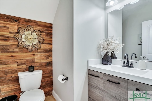 bathroom with vanity, toilet, and lofted ceiling