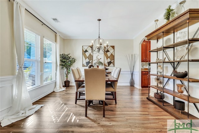 dining space featuring light hardwood / wood-style floors, crown molding, and a notable chandelier