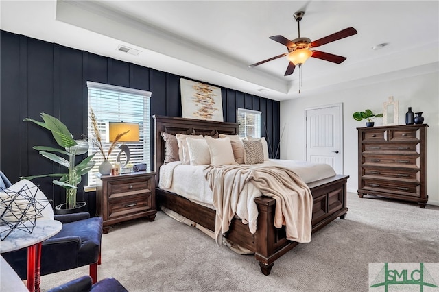 carpeted bedroom with ceiling fan, a raised ceiling, and a closet