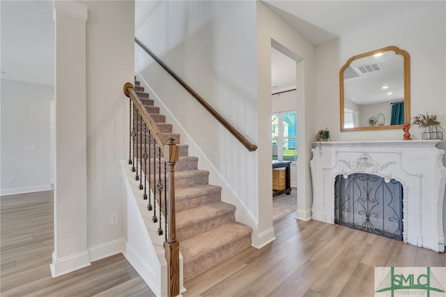 staircase featuring a fireplace and hardwood / wood-style floors