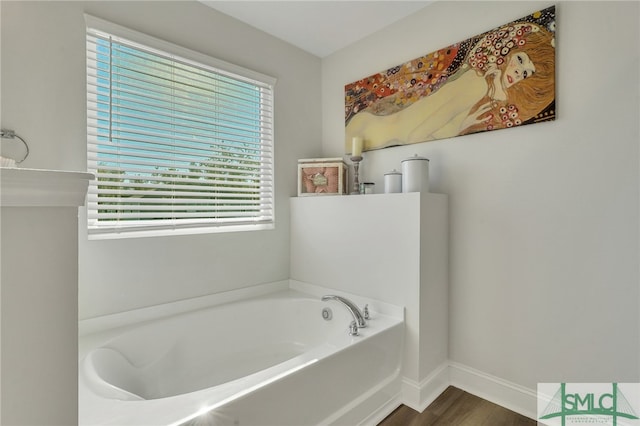 bathroom with wood-type flooring, plenty of natural light, and a bathing tub