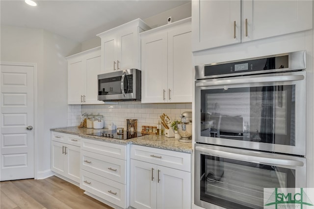 kitchen with backsplash, light hardwood / wood-style floors, light stone counters, white cabinetry, and stainless steel appliances