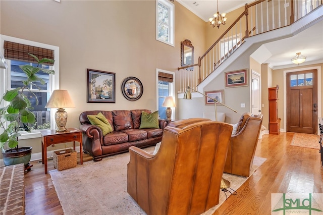 living room featuring a wealth of natural light, crown molding, a towering ceiling, and light wood-type flooring