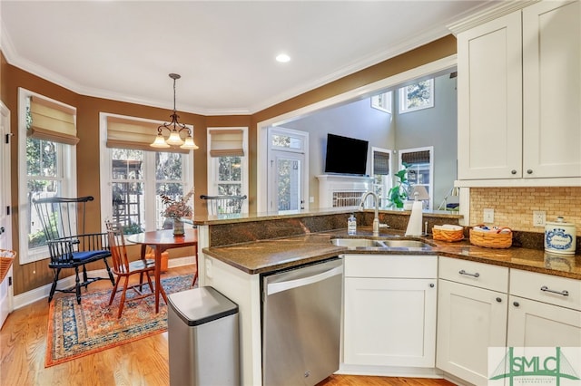 kitchen with dishwasher, light hardwood / wood-style flooring, dark stone counters, and sink