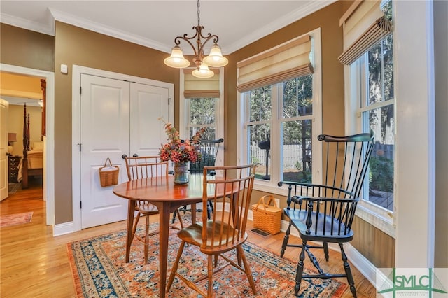 dining space with crown molding, light hardwood / wood-style flooring, and a notable chandelier