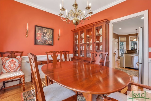 dining space featuring a notable chandelier, light wood-type flooring, and crown molding