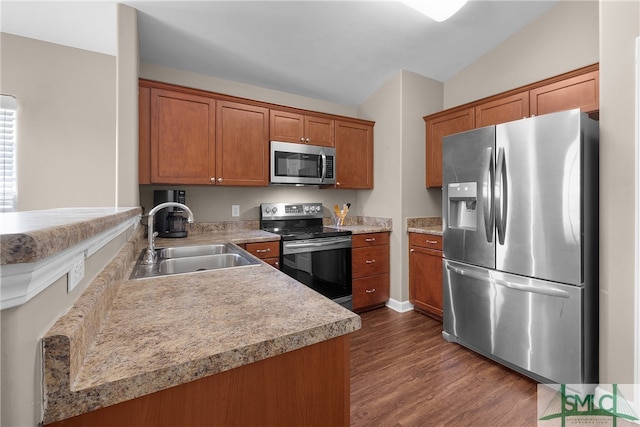 kitchen featuring kitchen peninsula, stainless steel appliances, sink, dark hardwood / wood-style floors, and lofted ceiling